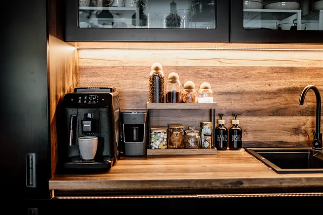 Cabinet and counter feature a coffee station with machines for brewing and grinding, jars of coffee, and decorative bottles. The setting shows a tidy kitchen space. Planning a coffee station starts with the sequence, not the shelf