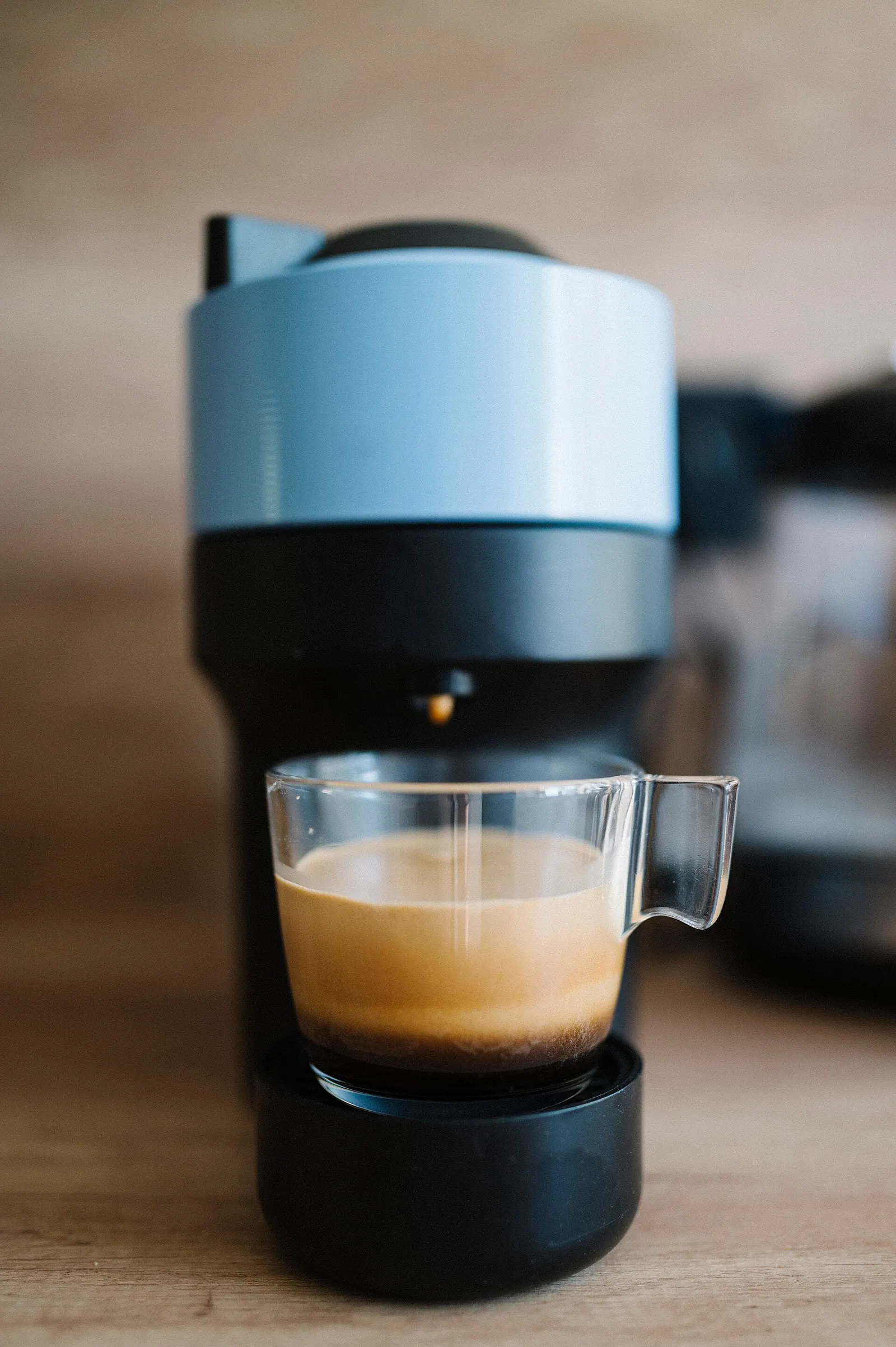 A coffee machine is brewing fresh espresso in a glass cup. The kitchen has a simple and clean look, with wooden surfaces and modern appliances. The moment captures morning routine. What to look for when buying from independent roasters: the useful version